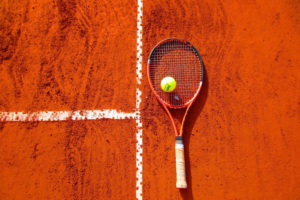 Raquette et balle de tennis sur court en terre battue